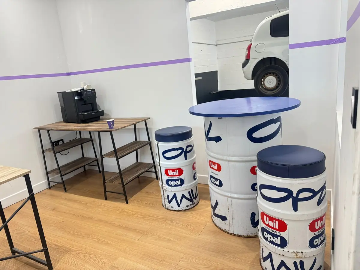 L’espace d’attente avec machine à café, tables et tabourets en fûts d’huile.